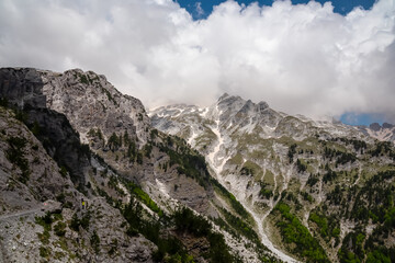 Obraz premium Scenic hiking trail surrounded by majestic steep mountain ridges of Albanian Alps (Accursed Mountains). Crossing high altitude pass between Valbone Valley and Thethi National Park, Albania. Wanderlust