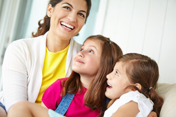 Obraz premium Hug, mom and comedy with children, house and affection for daughter, laughing and love for girls and family. Happy, mother and care for kids, relax and motherhood for woman, smile and embrace in home