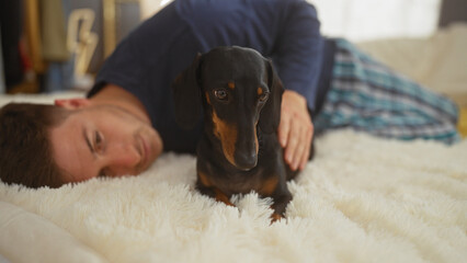 A young hispanic man lying on a bed in a cozy bedroom with his pet dachshund, creating a warm and...