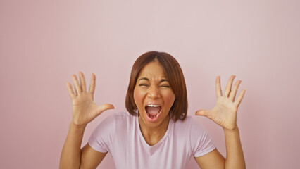 African american woman expressing excitement against a pink background with hands raised.