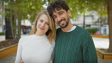 A happy couple embracing in a green city park during daylight.