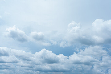 Fluffy white clouds drift across a bright blue summer sky