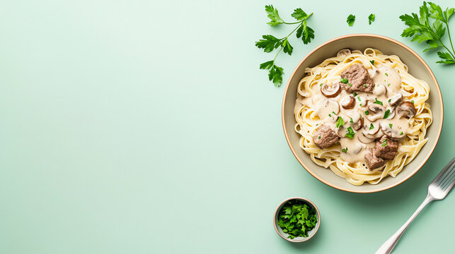 Delicious pasta with creamy sauce and herbs on a mint background, showcasing culinary delight and fresh ingredients in an elegant presentation.
