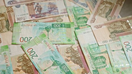 Fototapeta premium Russian banknotes of various denominations scattered on a surface, highlighting the ruble currency and depicting the financial theme intricately.