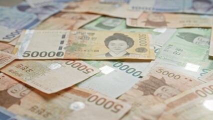 Fototapeta premium South korean won banknotes scattered with various denominations, showcasing south korean currency details vividly.