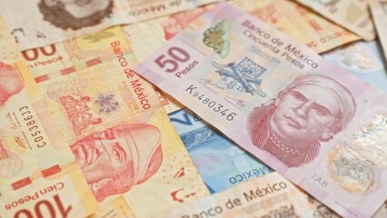 Mexican banknotes scattered with various denominations showing the intricate designs and vibrant colors of pesos currency in mexico