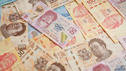 Colorful mexican banknotes of various denominations scattered in a pile, displaying vibrant designs and prominent figures representing currency in mexico.