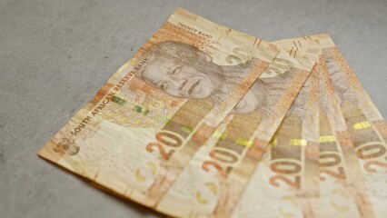 South african banknotes featuring nelson mandela's image fanned out on a concrete surface, showcasing the currency's design and national icon.