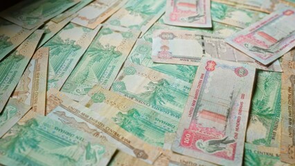 Fototapeta premium Scattered uae dirham banknotes showing various denominations of emirati currency, including ten, fifty, and one hundred dirhams, representing the united arab emirates economy.