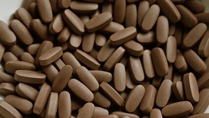 Close-up view of brown pills scattered randomly, showcasing medication and pharmaceutical concept without any people present