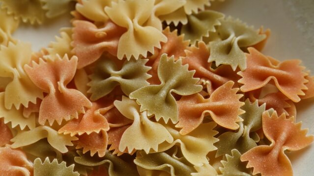 Colorful farfalle pasta close-up showcasing the texture and pattern of the bow-tie-shaped noodles in various shades of red, green, and yellow.
