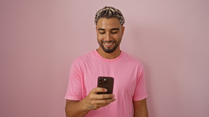 Fototapeta premium Young arab man with beard smiling at smartphone over isolated pink background