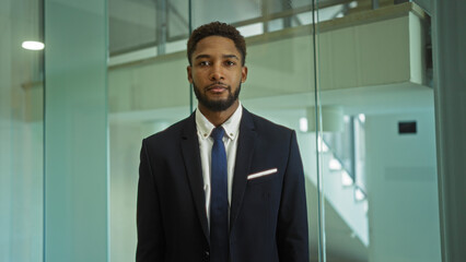 Fototapeta premium Young man in business attire standing in modern office interior with glass walls