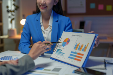 Two Asian businesswomen come up with an idea. Discuss investment projects and strategic planning with information via various documents and files. On a laptop computer at modern office.