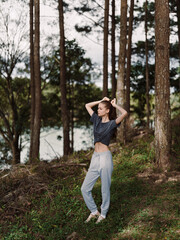 Young woman in casual sportswear stretching outdoors in a forest, surrounded by trees, showcasing a healthy and active lifestyle Nature and fitness concept