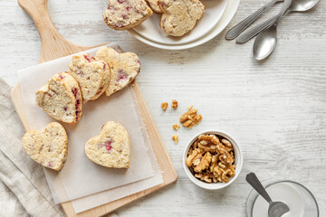 Heart shape scones on messy table, healthy coconut and walnut sweets for Valentine's Day