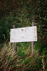Weathered blank wooden sign stands in a grassy field
