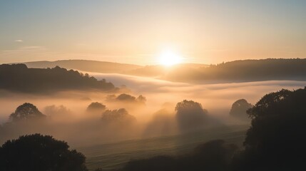 Obraz premium A foggy morning sky with faint sunlight breaking through the mist, casting a diffused glow over the landscape below