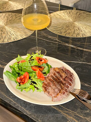 Glass of juice on the table and steak on the plate