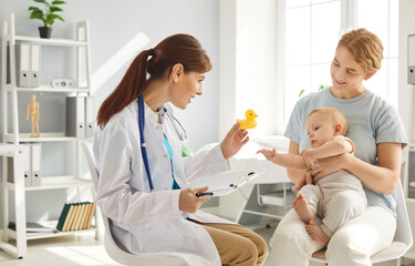Positive doctor pediatrician is consulting a mother and little baby in a hospital office. Medical...