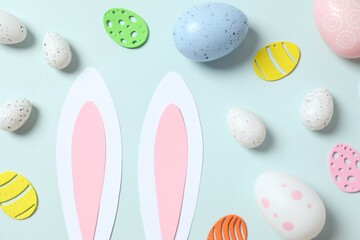 Easter decor concept. Top photo of Easter bunny ears, various eggs and Easter decor on colored background 