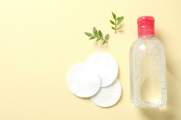 Micellar cleansing water and cotton pads on a color background, top view. Flat lay.