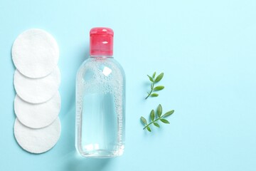 Micellar cleansing water and cotton pads on a color background, top view. Flat lay.