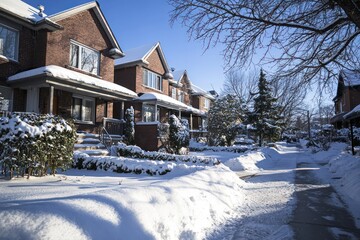 A family duplex in North America shows a snowy yard under winter sunlight.