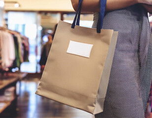 Hand holding shopping bag in supermarket Aisle with Blurred Shelves in Background.