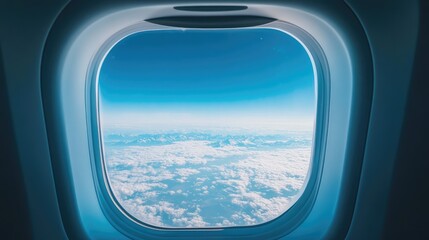 A beautiful blue sky with distant mountains visible below through an airplane window, with light clouds drifting across the horizon