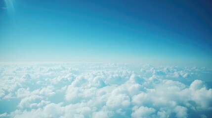 Fototapeta premium A clear blue sky with soft white clouds seen from an airplane window, with the wingtip visible against the vast horizon