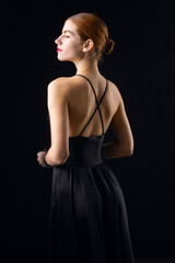Fototapeta premium A young redhear girl with clean skin wearing black gloves. Beauty portrait of a woman on a black background in the studio.
