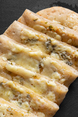 Sliced garlic cheese and herb flat bread. On a grey slate stone background