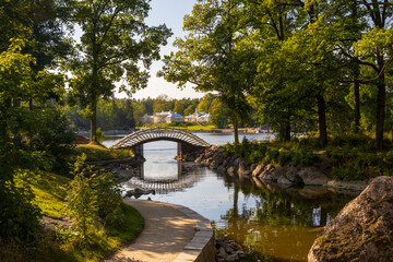 Monrepos Park, Vyborg, Leningrad Oblast, Russia. View of the Chinese Bridge (a wooden pedestrian bridge leading to a small island). The buildings of the Monrepos estate are visible in the distance.