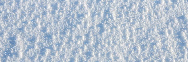 Natural snow texture. The surface of an icy snow crust. Snowy ground. Winter background with snow patterns. Perfect for Christmas and New Year design. Closeup top view.