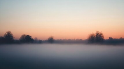 Fototapeta premium A misty morning sky with pale orange and pink hues barely visible through the light fog, creating a soft and dreamy scene
