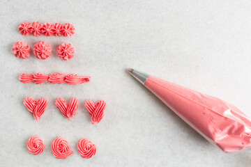 Pink buttercream piped on a granite countertop, buttercream piped using a piping tip on a white...
