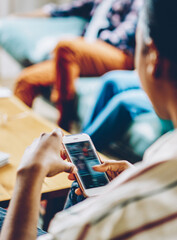 Crop African American woman surfing cellphone during meeting with friends