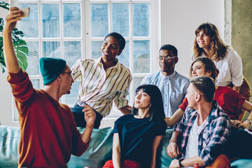 Multiethnic casual students making selfie on smartphone at home party