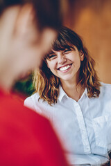 Curly woman with wide smile looking at colleague in multiracial group of people