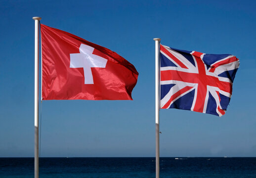 The national flags of Switzerland and the United Kingdom next to the sea