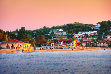 Beautiful scenic view - colorful pink sky at sunset above blue water of Aegean Sea, sand beach and...