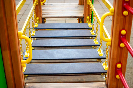 Explore the vibrant wooden playground featuring a bridge and playful colors in a modern residential area during a sunny day