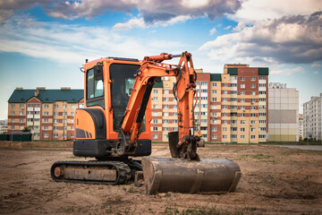 Powerful construction excavator working on a site surrounded by residential buildings during the day