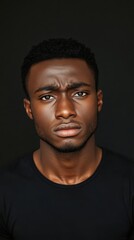Fototapeta premium Intense Portrait of a Young Black Man Against a Dark Background