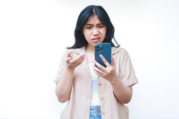 Fototapeta premium confused asian woman using smartphone with raised palms show uncertainty expression wearing casual clothes isolated on white background