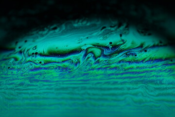 Bright rainbow reflection of liquid in macro, blue and white colors, rainbow background