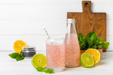 Diet detox cocktail with basil and chia seeds in a glass jar and a glass on a textured background....