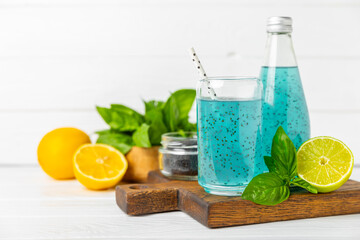 Diet detox cocktail with basil and chia seeds in a glass jar and a glass on a textured background....