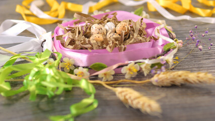 Fototapeta premium Eggs in the nest decorated with ribbons and flowers. Easter celebration concept.